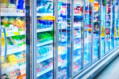 Allée de réfrigérateurs commerciaux dans un supermarché avec portes vitrées révélant des produits alimentaires emballés colorés sur plusieurs niveaux d'étagères