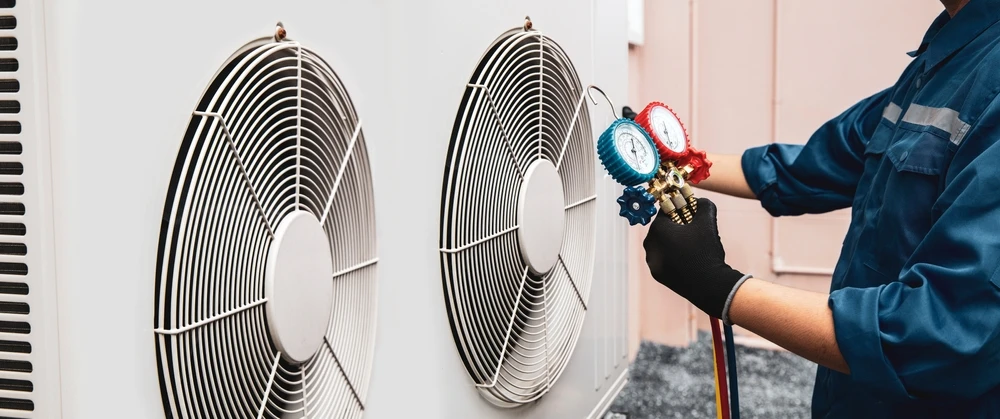 Technicien en combinaison de travail effectuant une inspection sous un équipement de chauffage ou climatisation