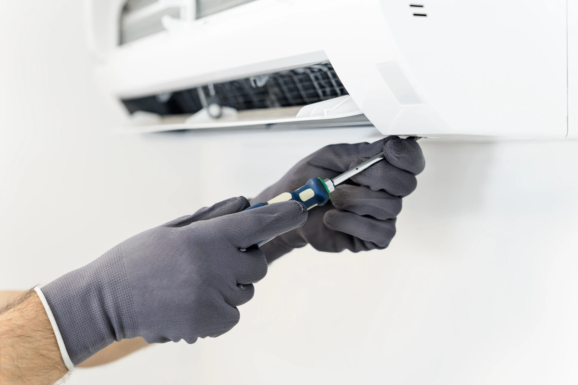 Technicien en tenue de travail bleue effectuant maintenance sur système de climatisation résidentiel